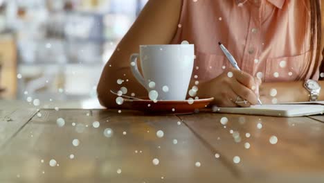 woman writing on her notebook against bokeh effect