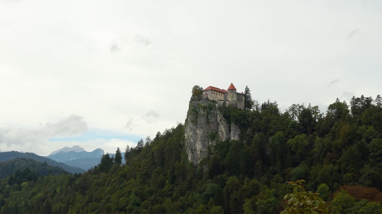 Castello di Bled sulla scogliera con fitta foresta sopra il lago in Slovenia. - Inquadratura con zoom indietro