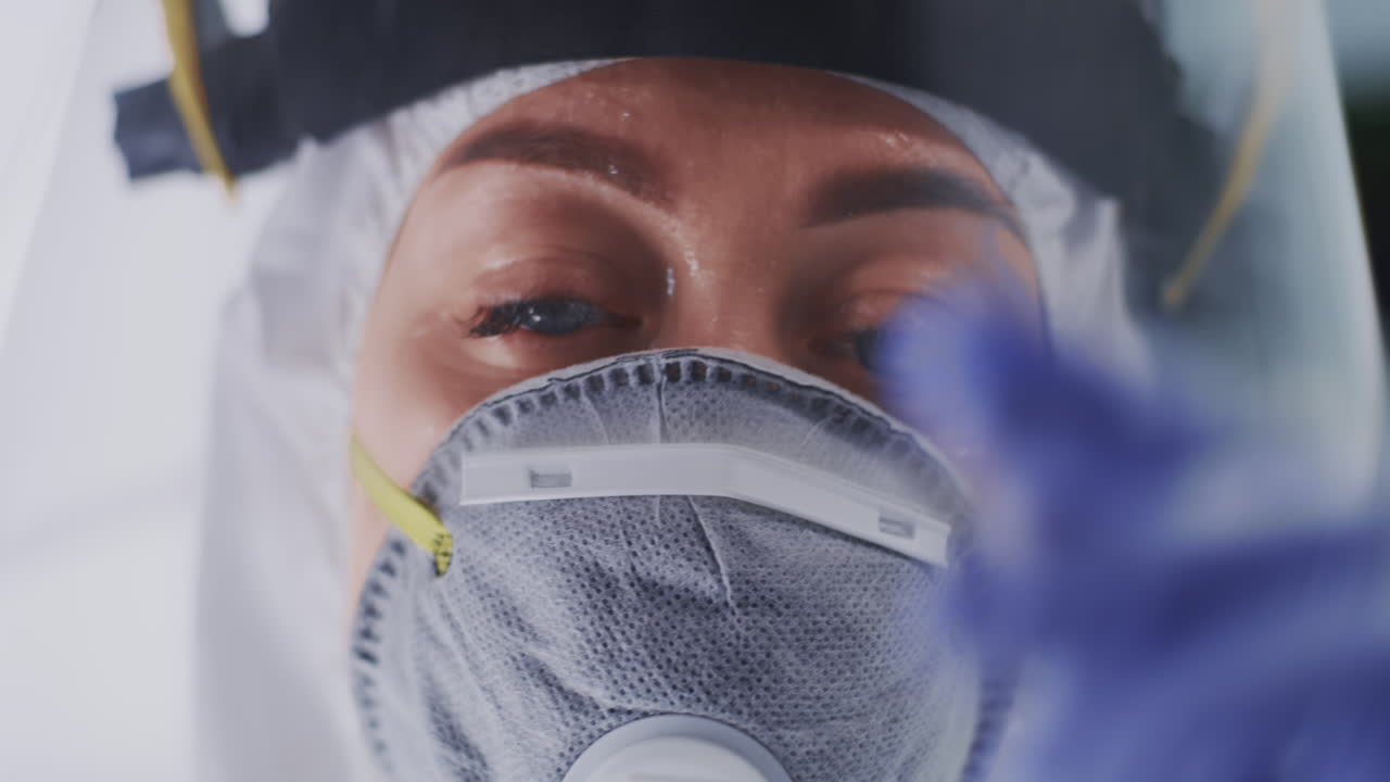tired Doctor Taking off Respirator and Face Shield Closeup Female Medical Practitioner with Sweaty Face Taking off Mask and Face Shield Looking at Camera in Coronavirus Clinic