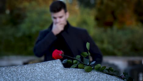 man standing in front of a grave sad