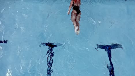 a woman swimming in a pool reaches the end of the lane and turns to complete another lap - overhead slow motion