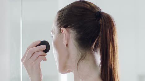 Profile-side-view-of-caucasian-woman-dabbing-makeup-on-her-face