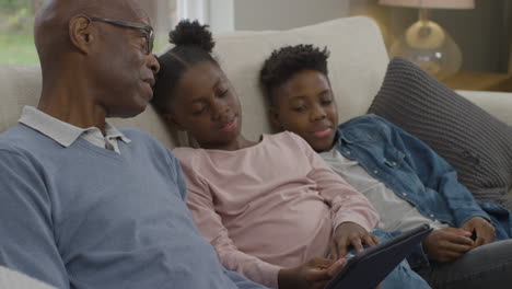 Abuelo-Leyendo-Un-Cuento-En-Una-Tableta-Electrónica-A-Sus-Nietos