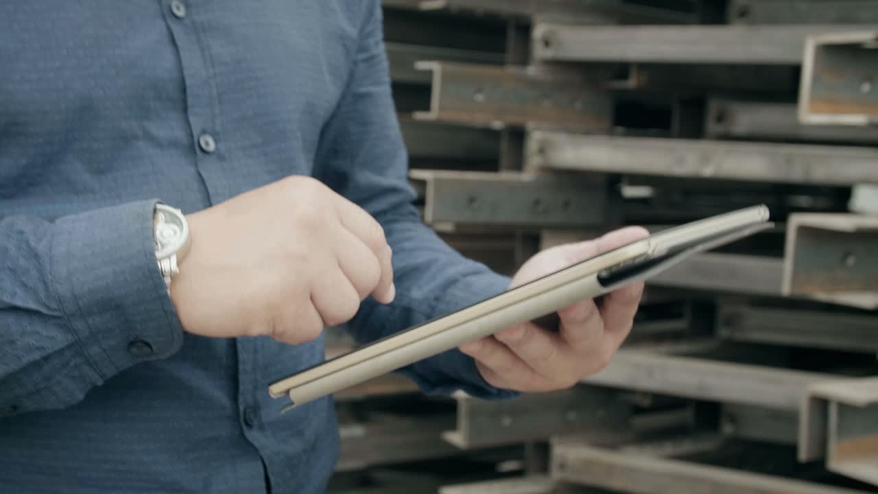 Man using tablet in a metal warehouse