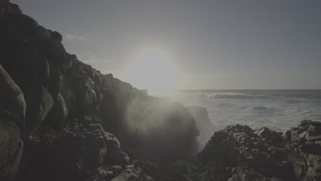 powerful waves crashing on volcanic rocks at sunset