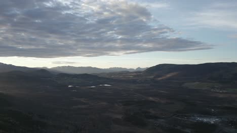 scenic aerial views of a serene valley at dusk and distant mountains under a cloudy sky.