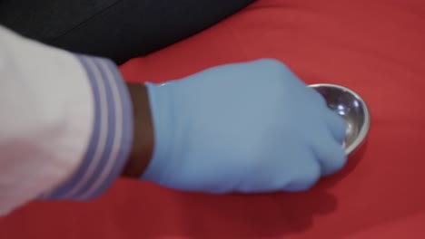 close up of hand of african american doctor holding blood samples from kidney dish on red background