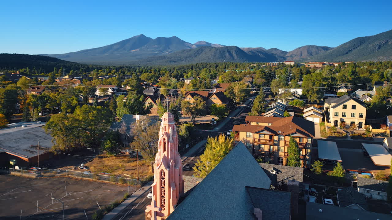 Flying over the stunning Gothic church of the Nativity in Flagstaff, Arizona, USA. Beautiful green panorama of the city surrounded by the mountains