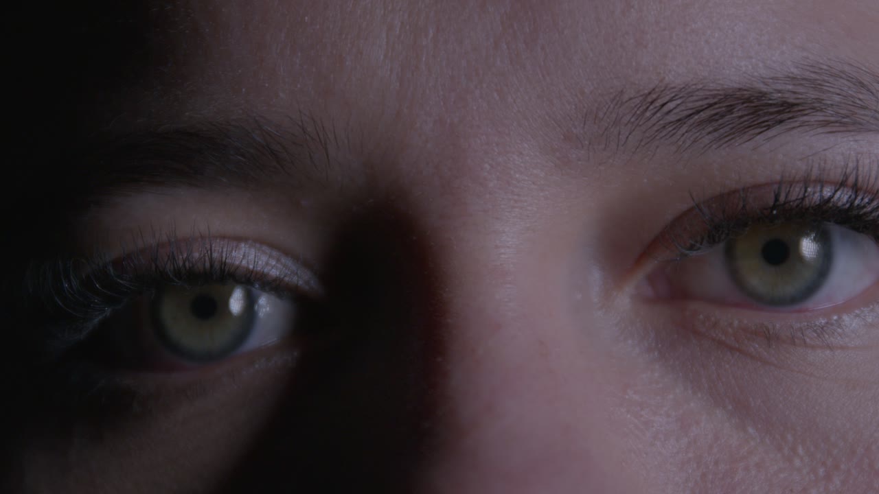 A captivating close-up shot of a girl's expressive eyes, highlighting intense focus and emotion. The dramatic lighting emphasizes the striking gaze in this intimate frame