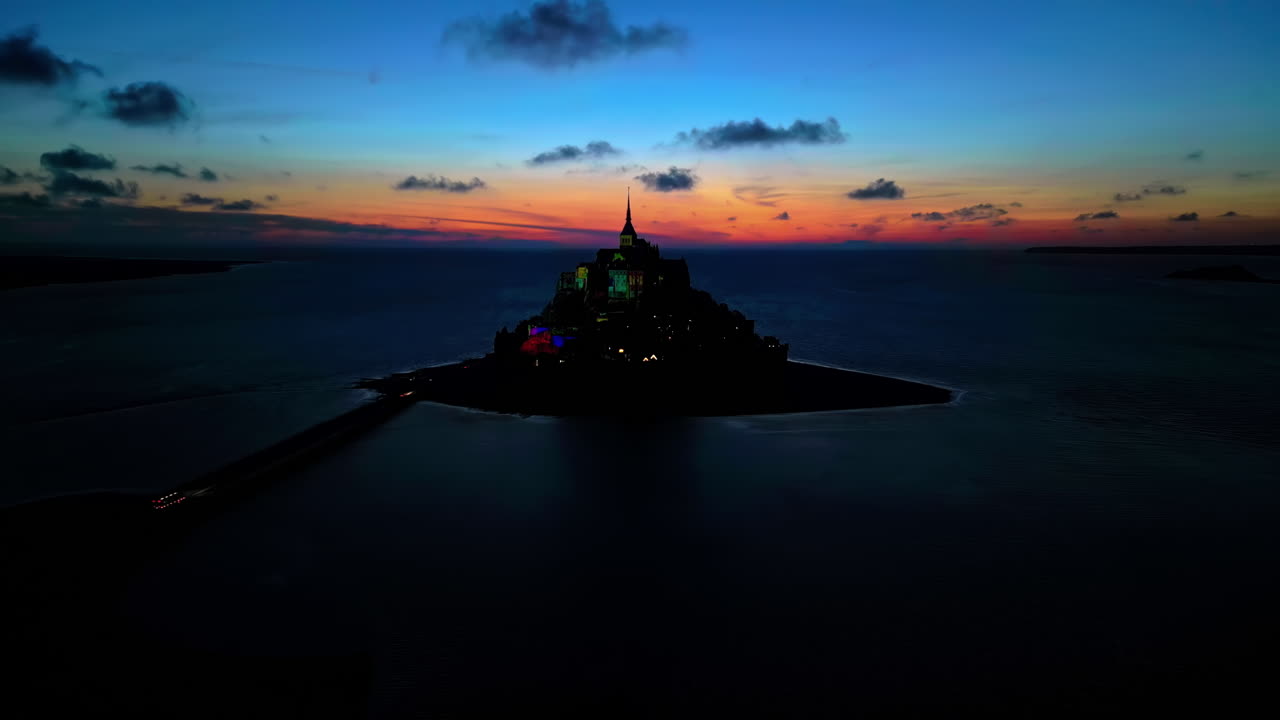 Aerial drone view of Mont-Saint-Michel at sunset in Normandy, France. Illumination in the town, water of the English Channel