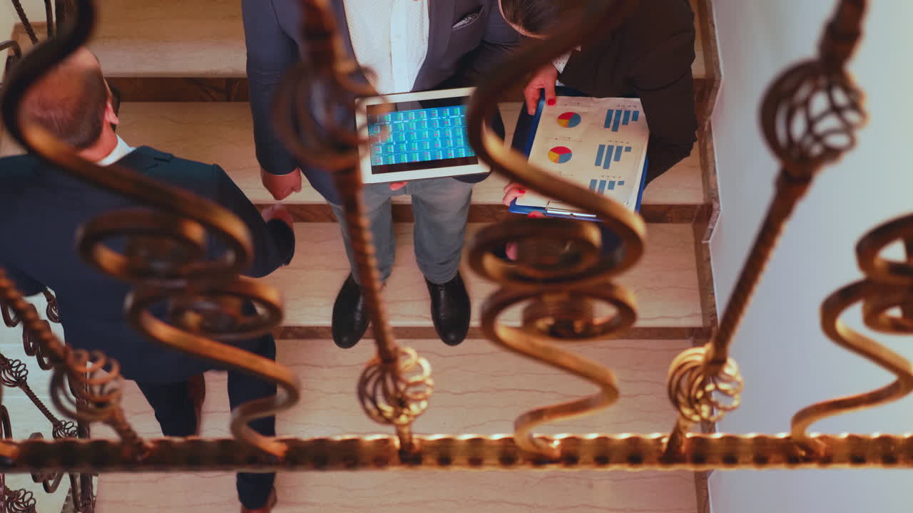Bovenaanzicht van collega's die samenwerken onder tijdsdruk, staand op een trap.