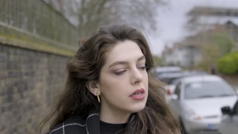 brunette businesswoman walking into shot on sidewalk drinking coffee in central london