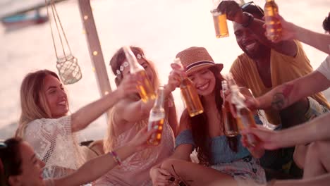 young multi-ethnic hipster friends toasting with beer at beach party