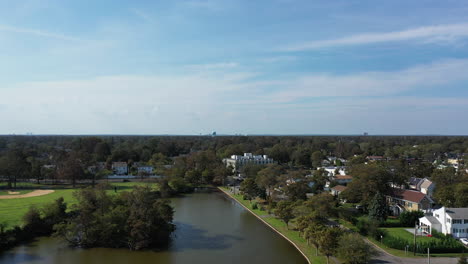 An-aerial-drone-shot-over-a-green-pond-in-a-suburban-neighborhood-on-Long-Island,-NY