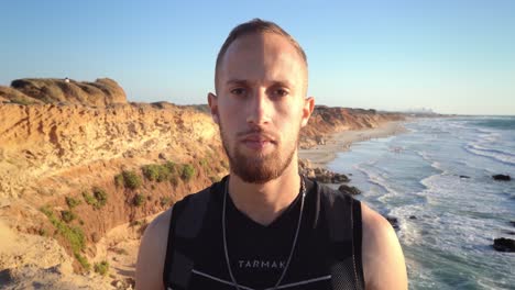 un hombre inteligente quitando gafas de sol con una hermosa playa dorada y olas en el fondo