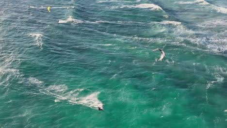 Slow-motion-aerial-drone-view-of-skilled-kite-surfers-in-green-azure-turquoise-ocean-in-South-Africa