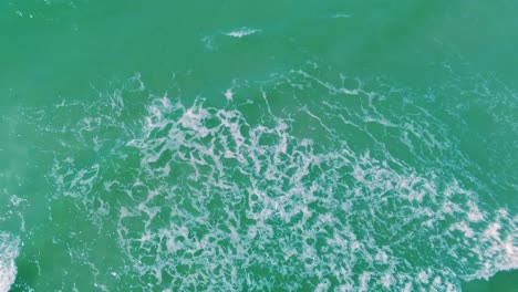 exotic tropical waves rolling towards ocean shore, aerial top down view