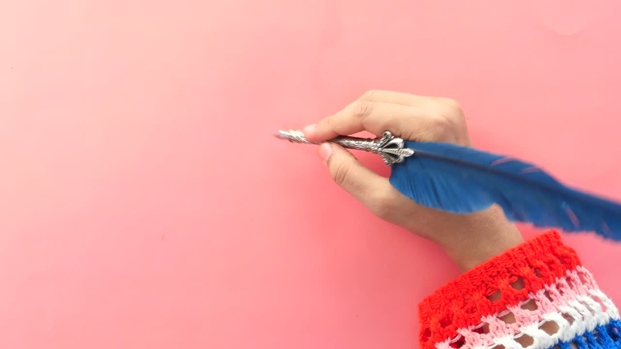 Hand Writing with Quill and Ink Pen on Pink Background