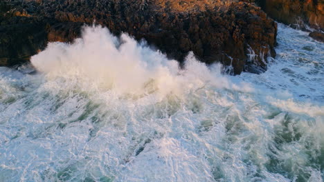 dramatic aerial sea crashing of dark coastal rocks closeup. ocean waves breaking