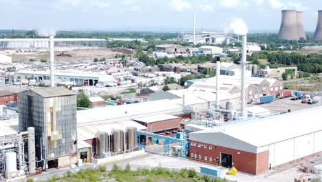 Industrial-warehouse-power-plant-refinery-buildings-under-smokestack-wasteland-aerial-view-push-in-right