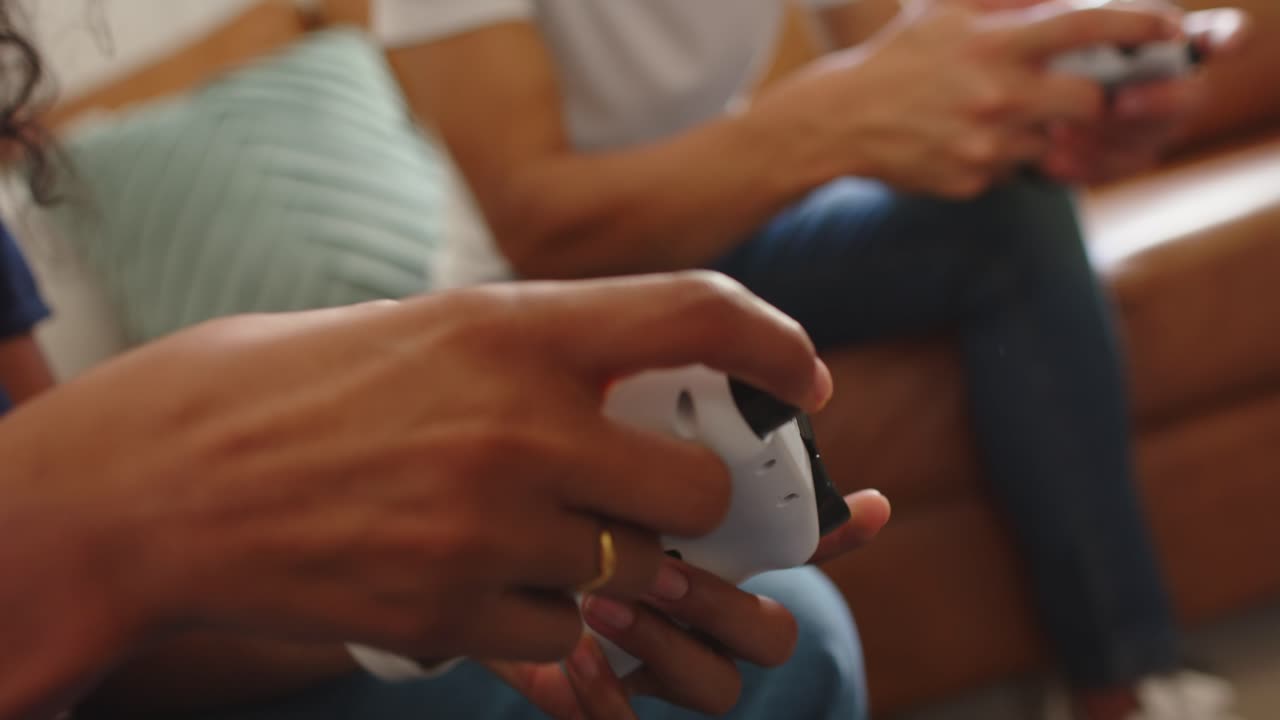 African couple starting game, hands moving stick, pressing blue buttons on controller on tan couch