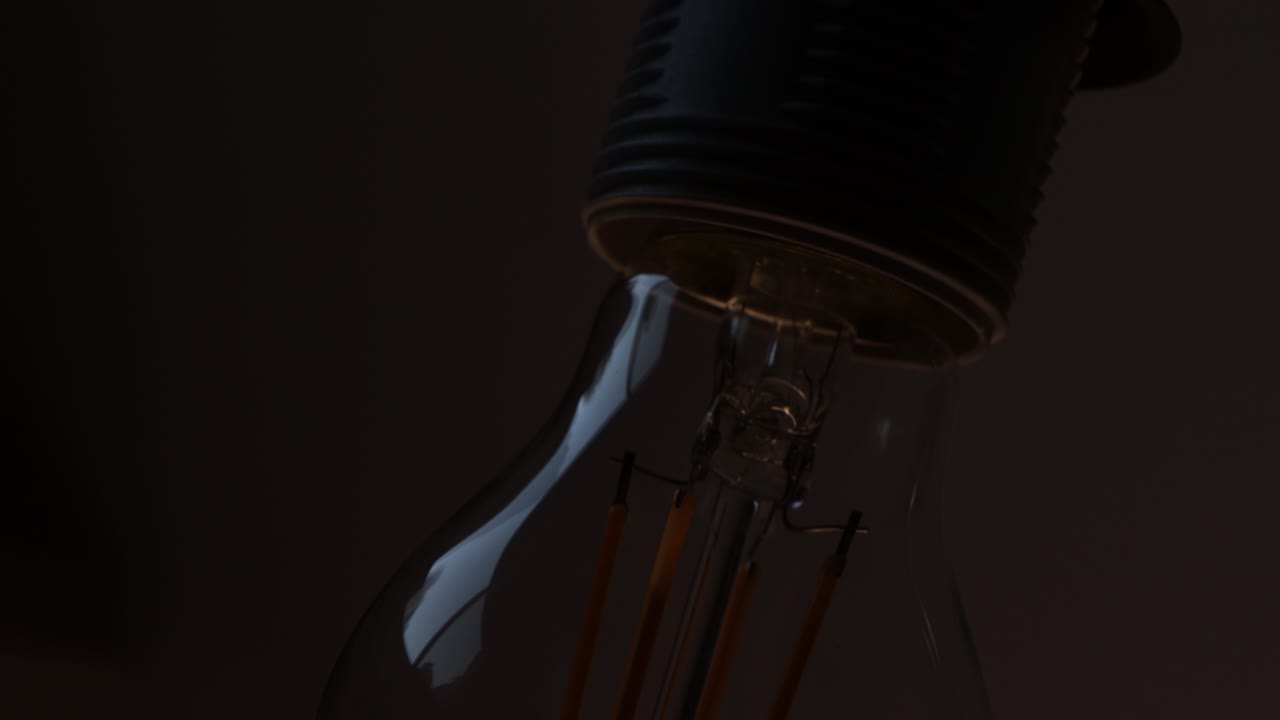 Tilting down clear lightbulb turning on and off close up