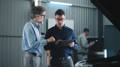 mechanic and customer discussing car repair in an auto shop