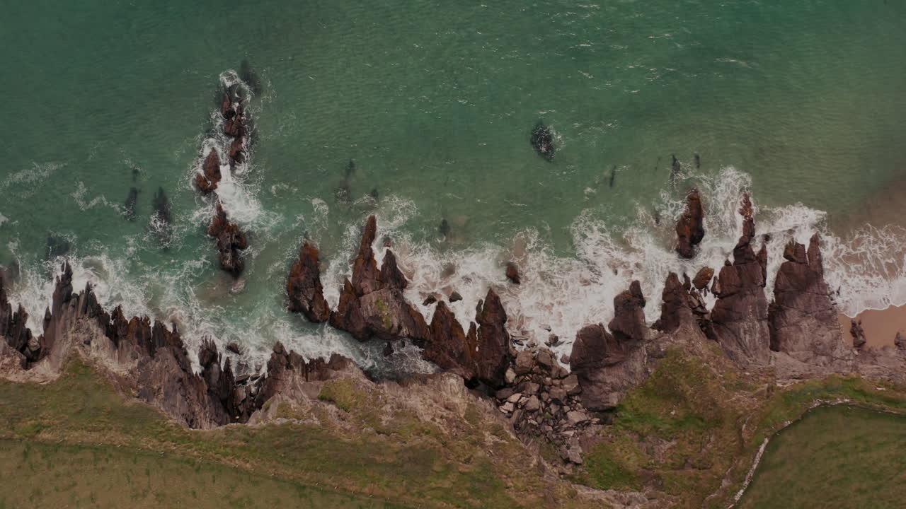Aerial view of a rocky coastline with waves crashing on the shore