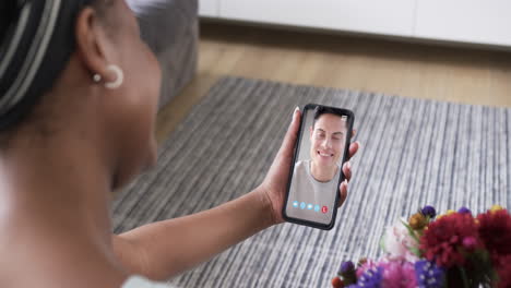 African-american-woman-holding-smartphone-with-caucasian-man-on-screen