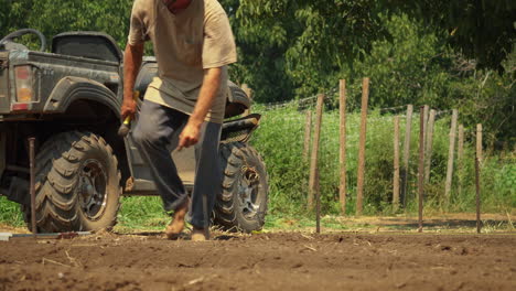 farmer setting stakes that will serve as a guide for plowing a crop field, hard worker concept