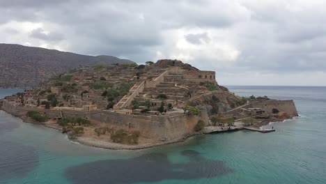 fly along with the drone as it approaches the old forts on an island, with a view of the mountains in the distance
