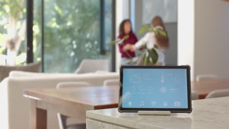 displaying weather and controls, smart home device with lesbian couple talking in background