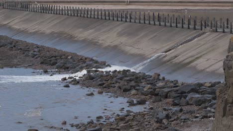 Water-being-released-from-the-artificial-beach-in-Weston-super-Mare-into-the-sea,-waves-crushing-into-the-rocky-beach