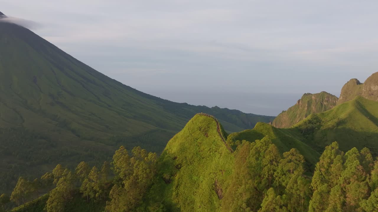 Matahari terbit di atas Gunung Inerie yang aktif dan kanopi hutan, Flores, Indonesia