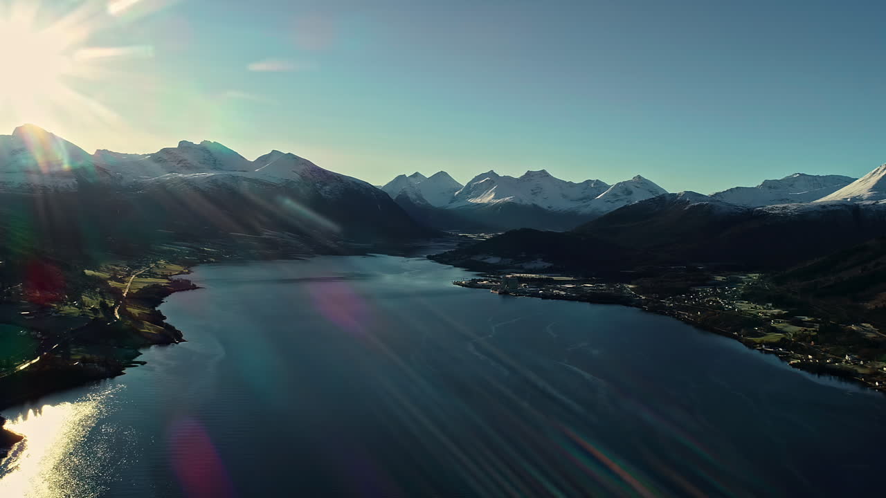 cinemática de drones aéreos sobrevolando el fiordo con casas de pueblo a lo largo de la ladera de la montaña en noruega en un día soleado