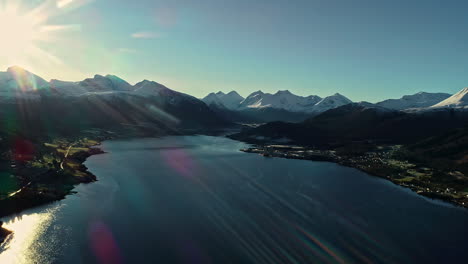 aerial drone cinematic flying over fjord with town houses along mountain slope in norway on a bright sunny day