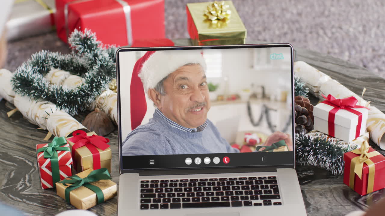 amigos diversos con sombreros de papá noel teniendo una llamada de video portátil con un hombre biracial feliz