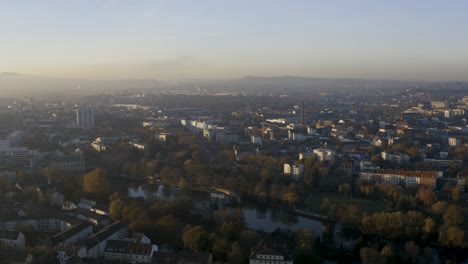 Toma-De-Drones-Del-Paisaje-Urbano-De-Kassel-En-Una-Hermosa-Luz-Solar-Suave-Y-Cubierta-De-Niebla