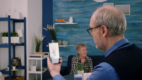 Retired-male-holding-smartphone-during-online-consultation