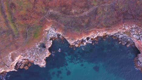 top down aerial view of waves splash against rocky seashore, background