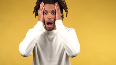 portrait of young afro american man shocked and confused, yellow background