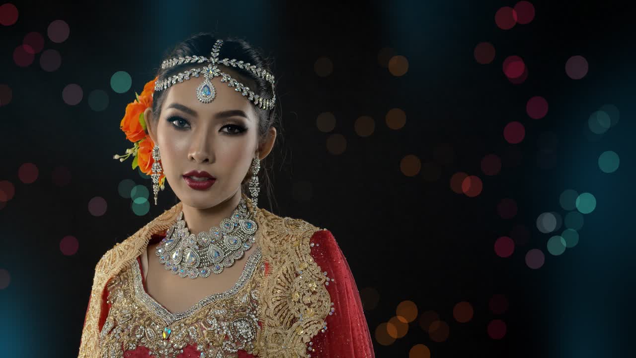 Beautiful and mysterious woman dressed in traditional Indian wedding Sari poses glamour portraits with bokeh and lights in the background
