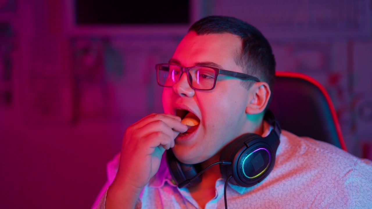 Ragazzo con occhiali e cuffie che mangia una patatina