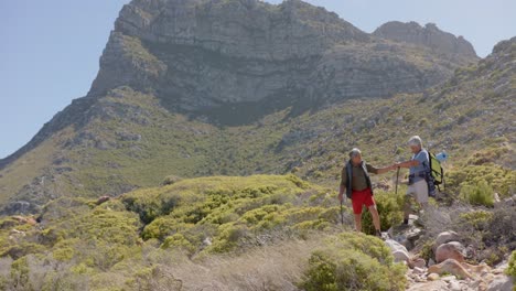 Happy-senior-biracial-couple-in-mountains-hiking,-in-slow-motion