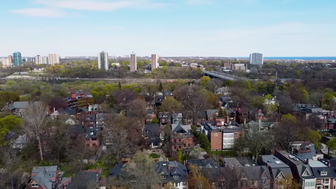 drone orbitando alrededor de las casas de toronto cerca de una carretera con el lago ontario en la distancia