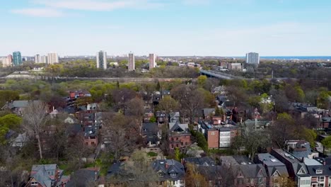 drone orbiting around toronto houses near a highway with lake ontario in the distance