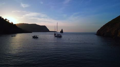 Sunset-behind-cliff-sailboat-silhouette