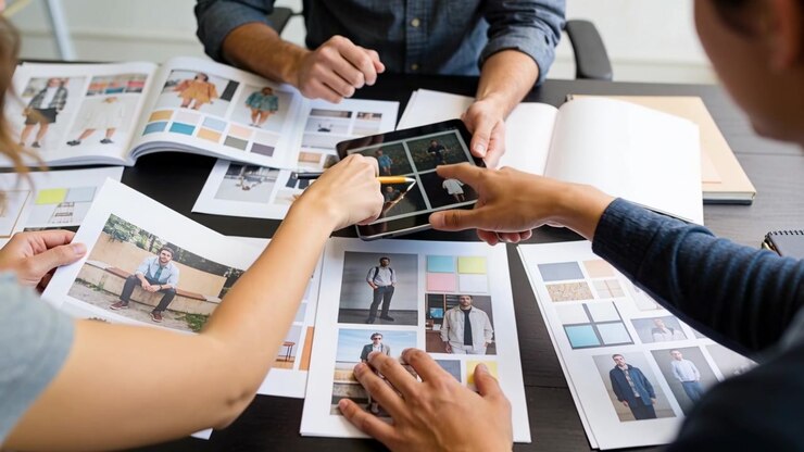 Tapping tablet, 3 designers in casual shirts comparing and selecting layouts at office with swatch