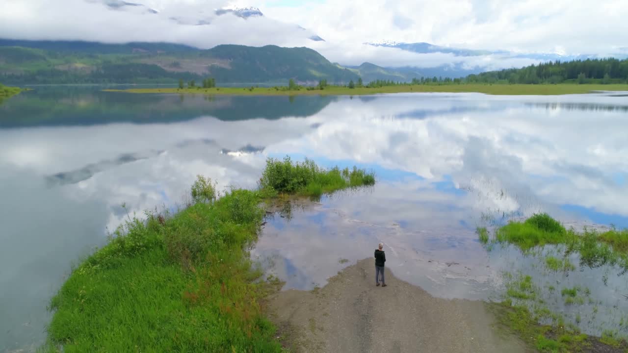 4k 호수 근처 에 서 있는 성숙 한 여자 의 공중 전망