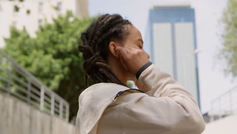 Side-view-of-young-African-American-woman-wearing-earphones-in-the-city-4k
